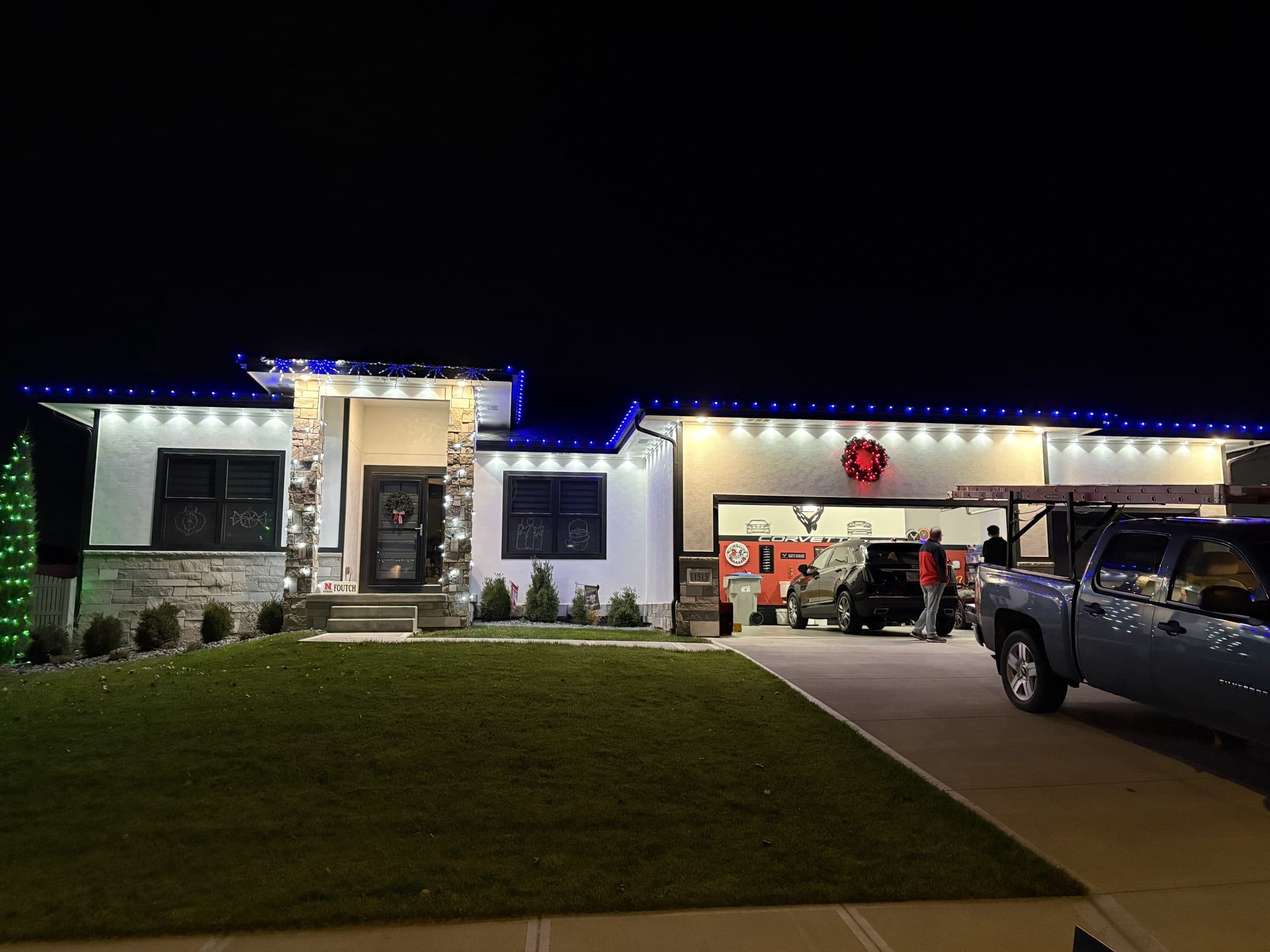 Wide view of a ranch home with blue eaves, warm white soffits and a wreath on the garage