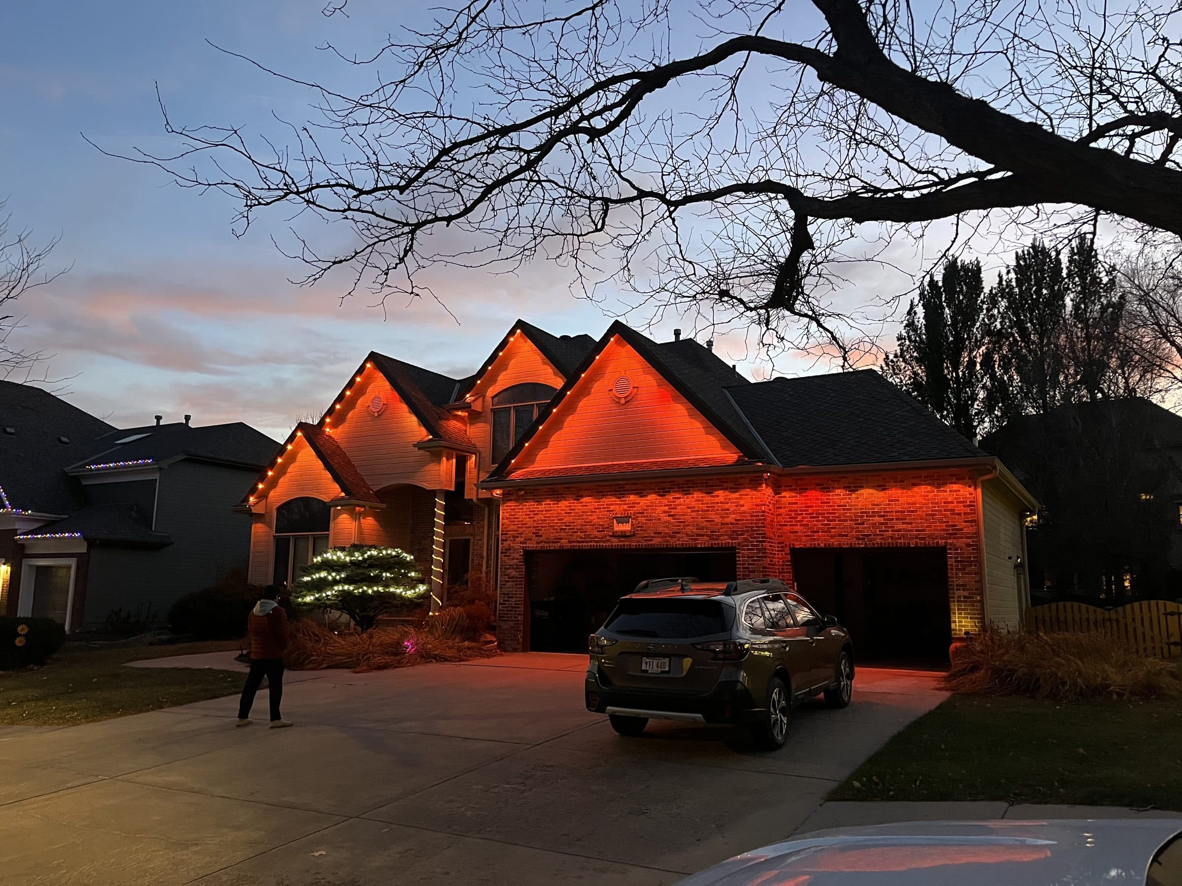 Brick home with orange lights washing the gables at dusk