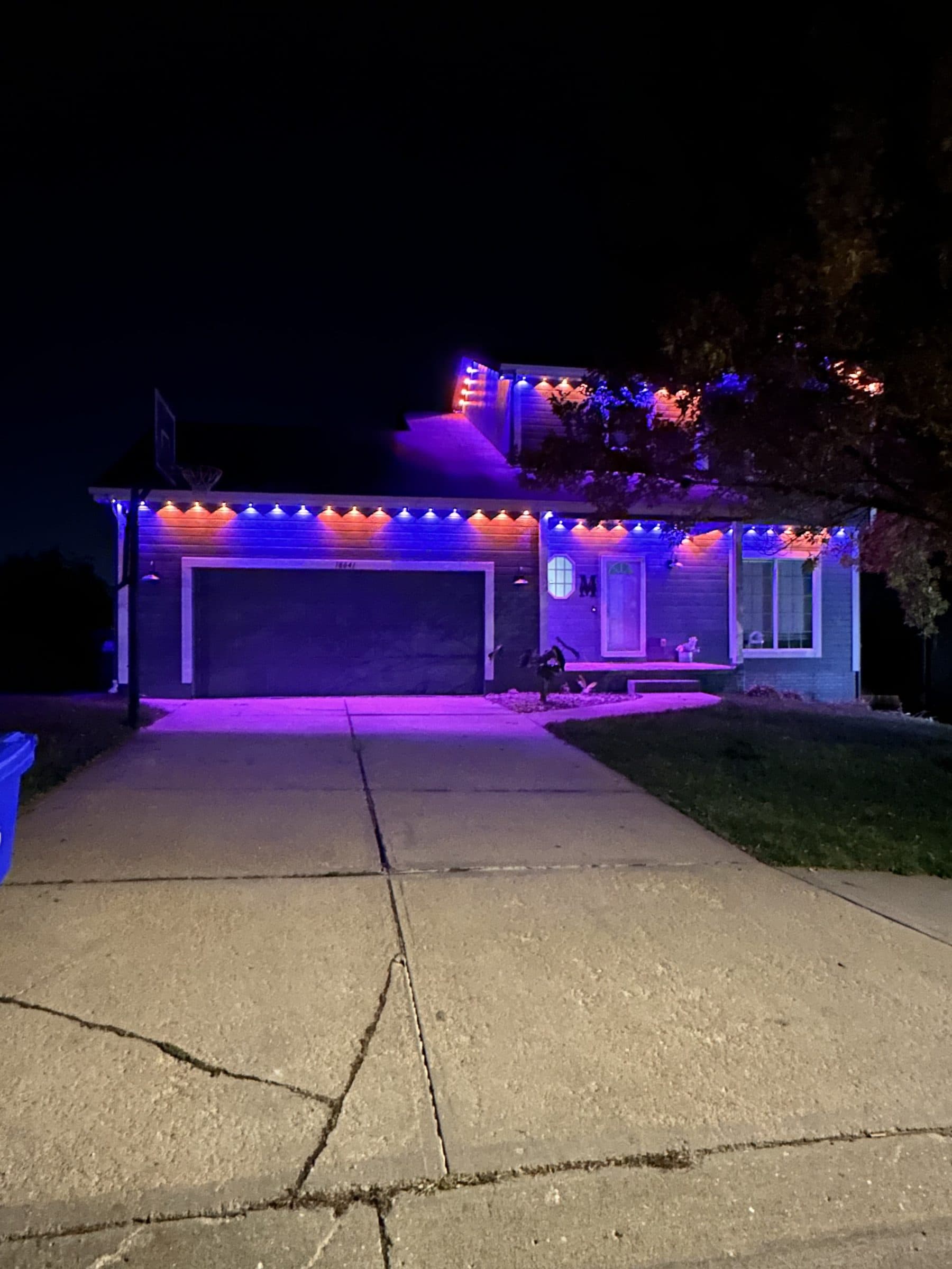 Home lit in purple and blue permanent lighting with a purple glow across the driveway
